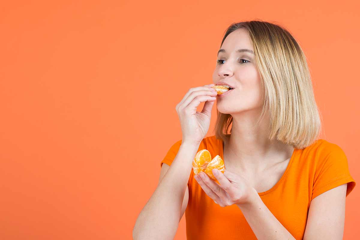 Donna che mangia un mandarino.